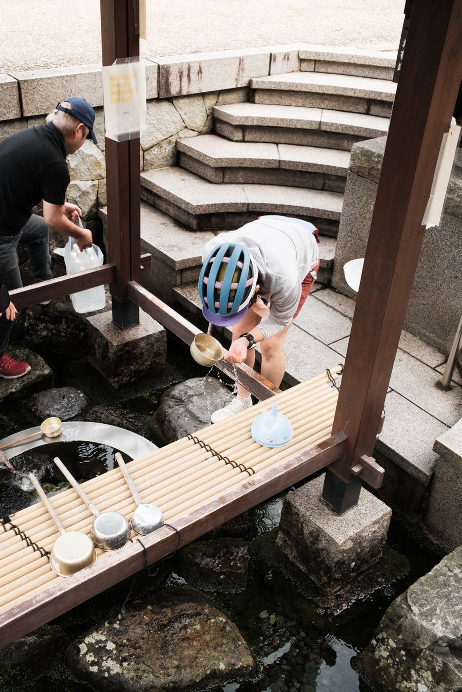 清水で、ひしゃくで水をくむ
