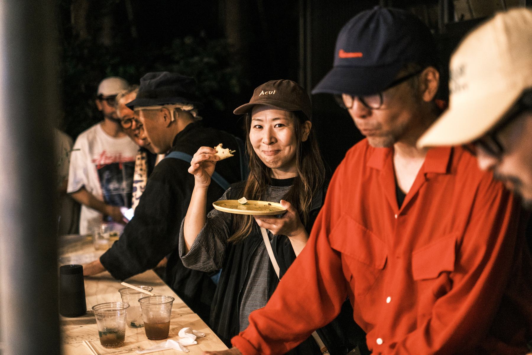黄色い器を手に、笑顔で料理を食べる