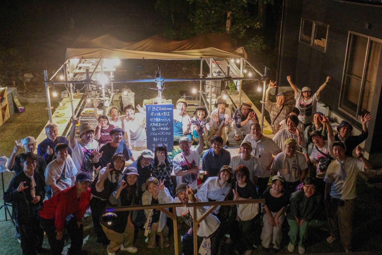 夜の会場で、参加者全員が手を挙げた集合写真